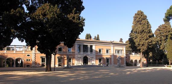 Photograph of a Roman villa with two floors and behind cypresses