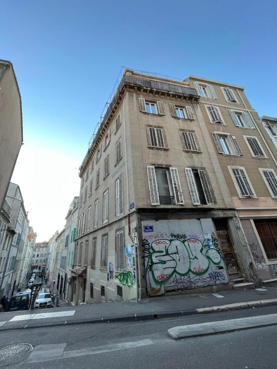 Mehrstöckiges Haus mit Fensterläden, das sich an einer Straßenecke befindet