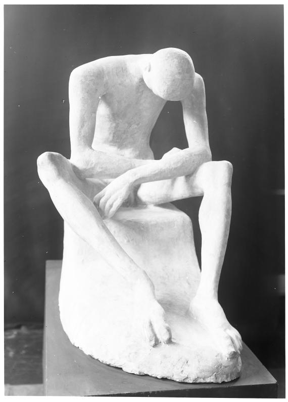 Black and white photograph of a light-colored sculpture against a dark background