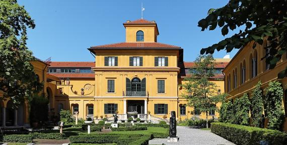 Historic villa and studio with yellow façade, elaborately landscaped gardens in front