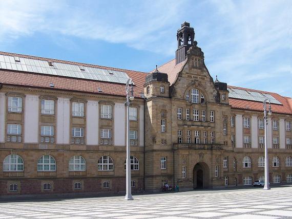 Photograph of a prestigious red granite building in a square location