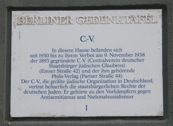 Gedenktafel mit blauer Schrift auf weißem Grund