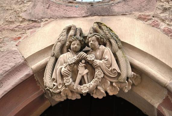 Photo of two stone putti at a doorway, holding a wreath and compass