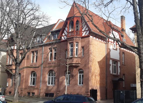 View of a reddish house with a pointed roof. Side view.