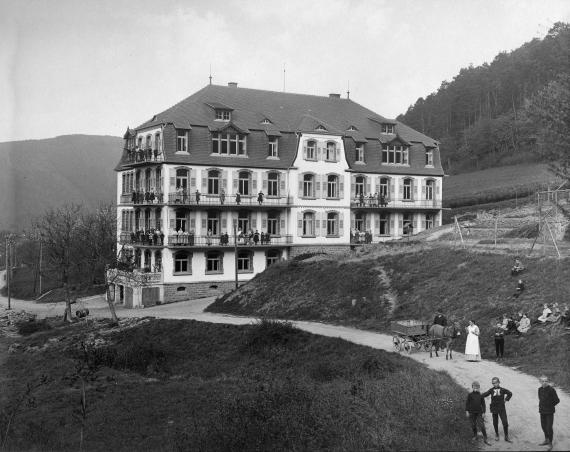 Schwarz-Weiß Bild. Ein Gebäude, das weiter entfernt ist. Außen herum Wiesenlandschaft.