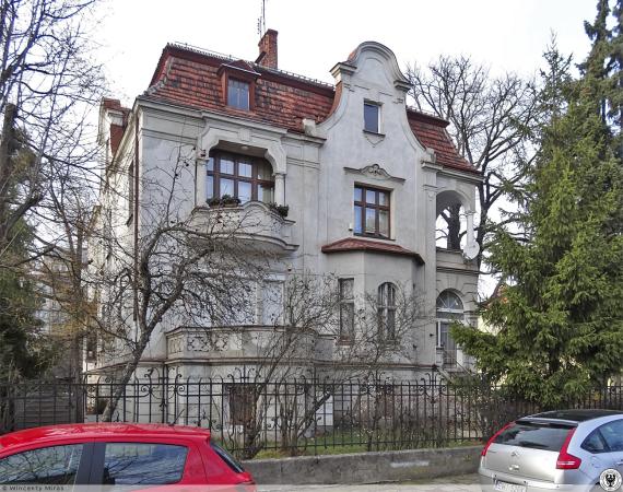 View of a stately home from the street. In front of it a fence.