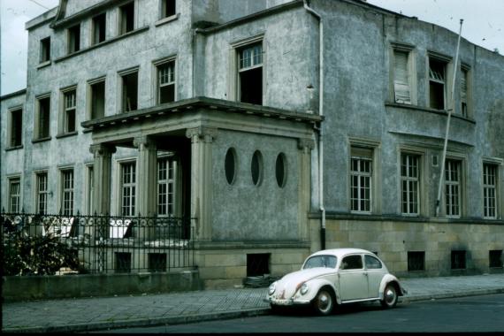 Side view of an old villa. In front of it an old small car.