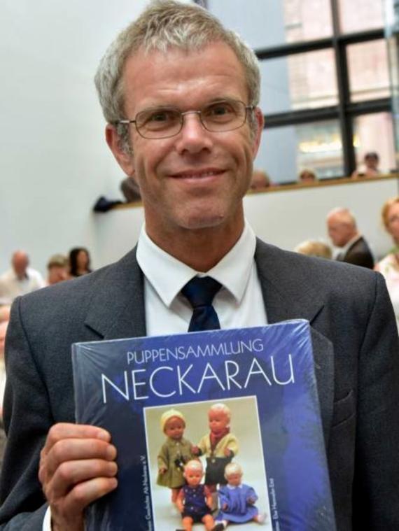 Portrait of a man pointing a book at the camera