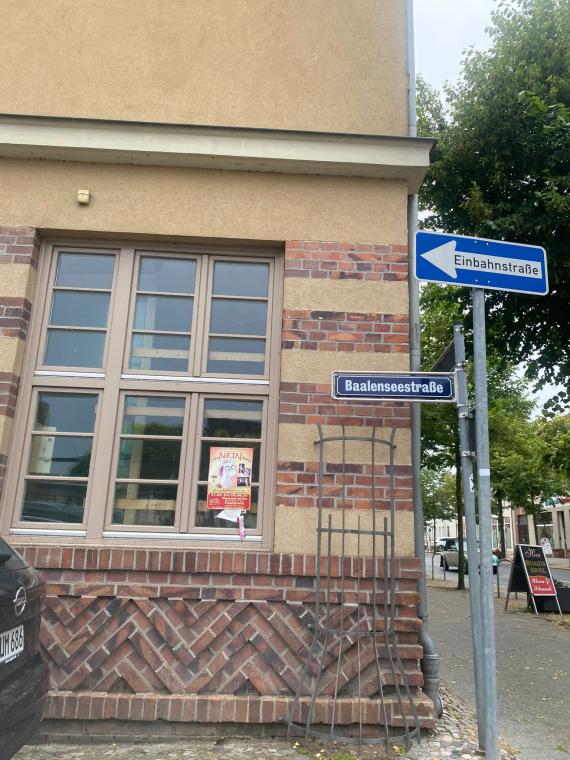 Auf dem Foto sieht man die heutige Baalenseestraße. Man erkennt Wohnhäuser, eine Straße und ein Auto. Auch sieht man ein blaues Straßenschild mit der Aufschrift Baalenseestraße. Es erinnert nichts an die einst dort stehende Synagoge.