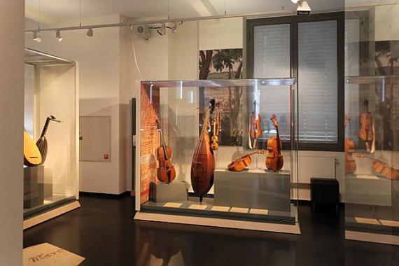 Eine aktuelle Fotografie der Ausstellung im Musikinstrumentenmuseum zeigt ca. ein Dutzend Streichinstrumente in Vitrinen