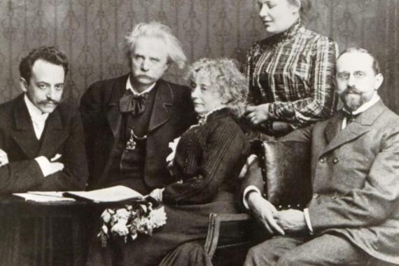 A group of five elderly men and women sit around a table