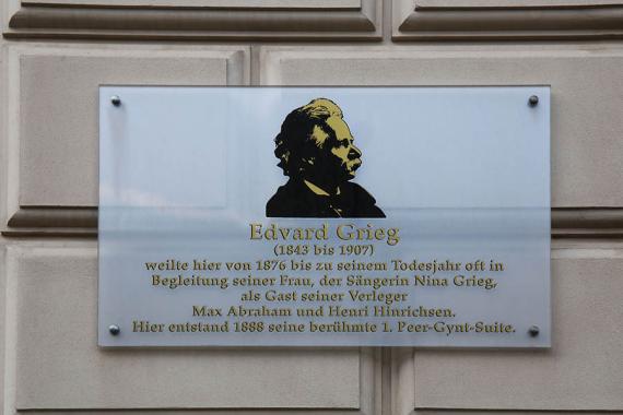 Die Gedenktafel für Edvard Grieg mit Porträtfoto und kurzem Text an der Mauer des Gebäudes