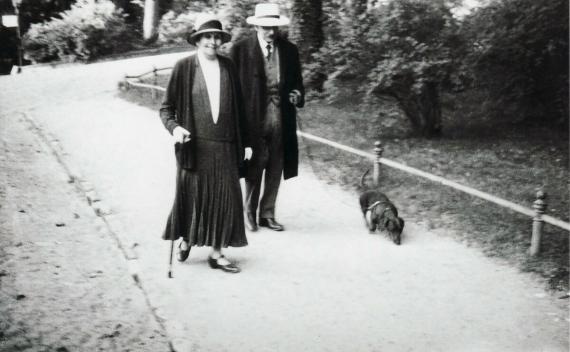 Ein fotografischer Schnappschuss in schwarz-weiß zeigt das Ehepaar Liebermann mit Dackel in einem Parkhepaar 