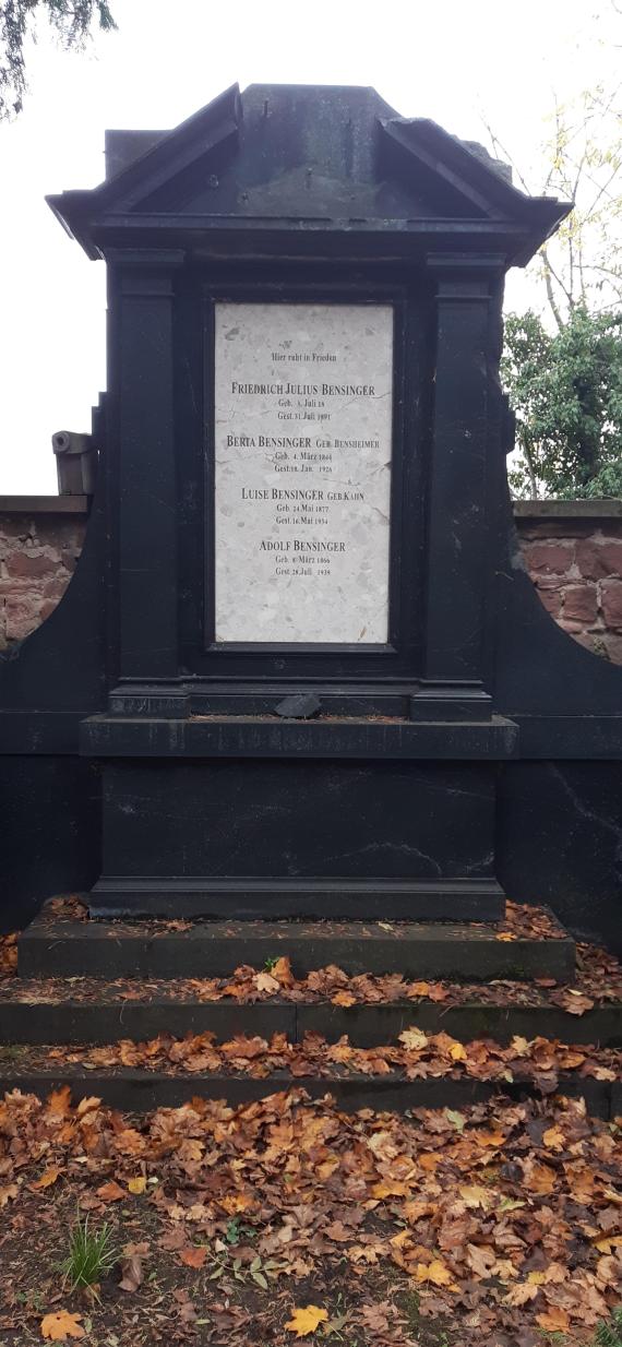 Large dark gravestone with a light-colored slab in the middle, with the following inscription