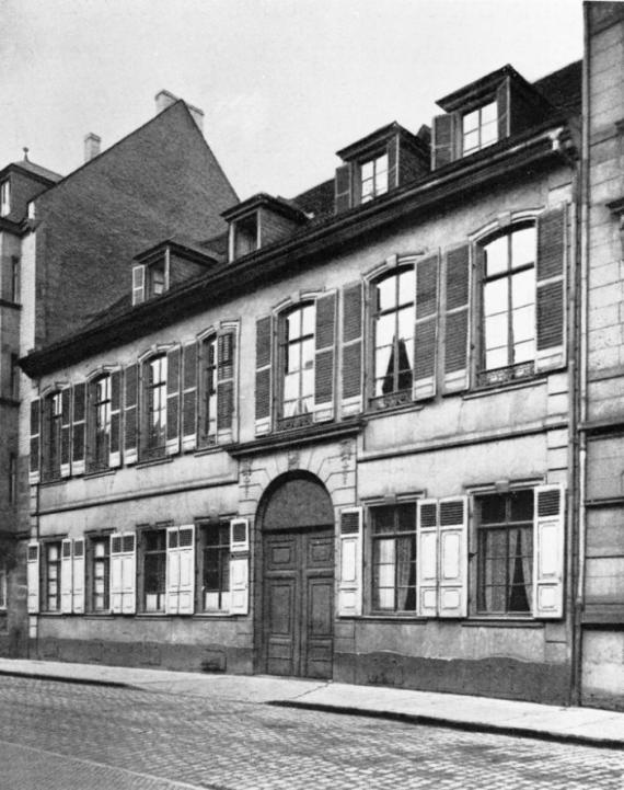 black and white picture of a terraced house complex, in front of it the street, side view