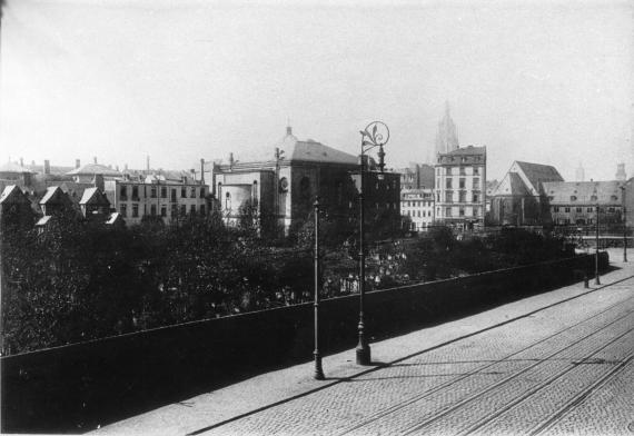 Abgebildet ist eine Straße, ein Friedhof und eine Synagoge im Hintergrund