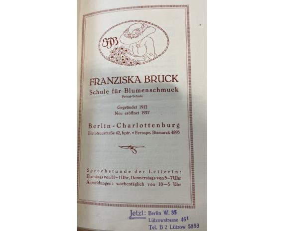 Titelblatt Broschüre: Franziska Bruck. Schule für Blumenschmuck (1927) The photo shows the cover of a brochure from Franziska Bruck's flower school. The name of her school is written on the page. Her school changed locations in Berlin several times: Potsdamer Straße, Bleibtreustraße, Lützowstraße. You can also see her logo. It consists of a woman with a basket of flowers and her initials SFB.