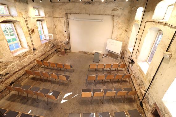 Blick in den Versammlungsraum vom Eingang der Frauenempore aus. Man sieht die Konzertbestuhlung und eine Wand, aus der der thoraschrein herausgebrochen wurde.