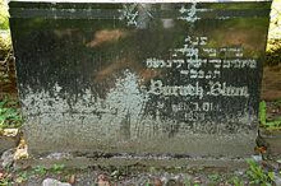 One of the lichen-covered gravestones, here with the inscription "Baruch [...] 1858 [...] 1929 [...]"