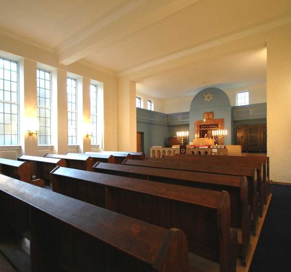 Interior to the Torah shrine. In front of the shrine, dark wooden benches are lined up in several rows.