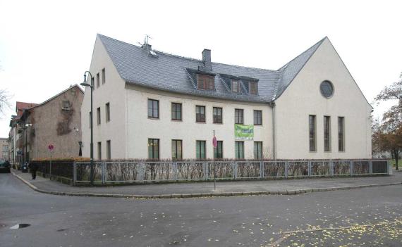 View from the east, you can see a one-zoned building with a pointed roof. Externally it appears like a residential building, it is the New Synagogue in Erfurt.