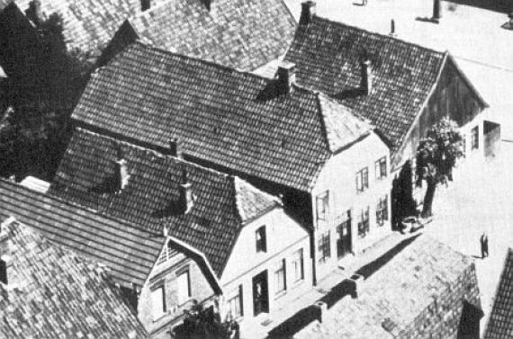 Black and white aerial view of the synagogue of Vechta. A row of four large houses with pointed roofs, the middle one is the synagogue