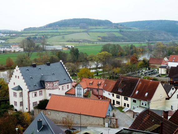 Schloss Laudenbach von erhöhter Perspektive aus. An der Westseite schließt sich ein kleiner Hofraum an, der von kleinen Häuschen gesäumt ist. Im Hintergrund sieht man das Maintal.