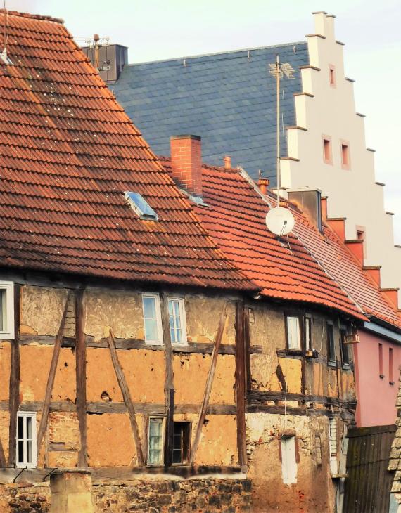 Zwei Häuschen des Judenhofes von Süden aus. Kleine, nicht verputzte Fachwerkhäuser, im Hintergrund das Schloss.