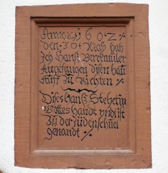 Inschrift aus rotem Sandstein am Haus der ehemaligen mittelalterlichen Synagoge in Karlstadt.
"Anno Domini 1602 den 30. Nov. hab ich Hanß Berckmüler Angefangen diesen bau Auff zu richten. Dieses Hauß steht in Gottes Handt und ist zu der Jüdenschuel genandt"