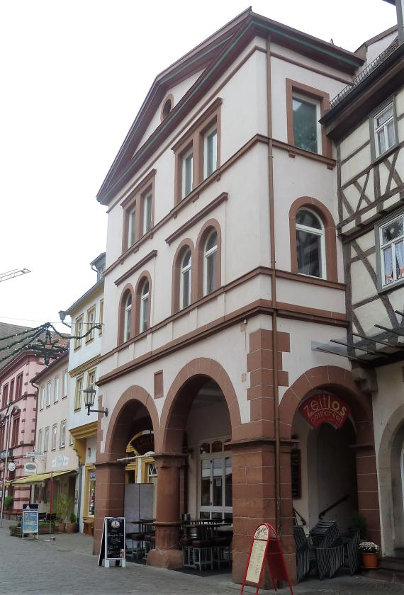 Mächtiges dreistöckiges Haus, aus Bruchstein gemauert. Es ragt mit seinen Arkaden weit in die Hauptstraße hinaus. Ursprünglicher Standort der Synagoge der ersten jüdischen Gemeinde.