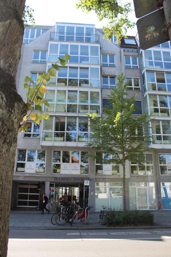 Front view of a multi-storey row house , in front of it a traffic road.