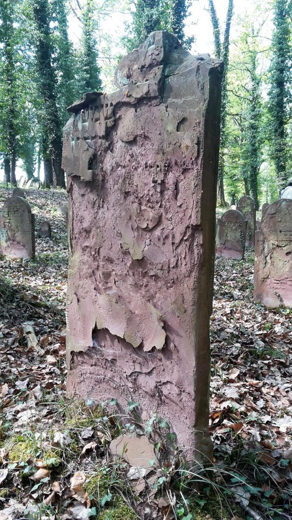 Gravestone made of red sandstone, the inscription has become completely weathered and illegible. Thus, every year anew a treasure is irretrievably lost.