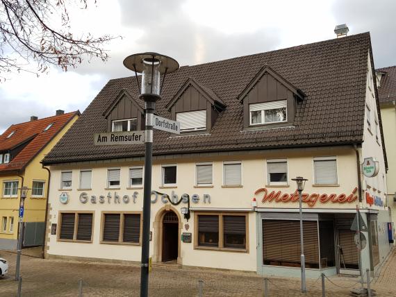 Im Vordergrund sieht man den Gasthof ochsen mit angebauter Metzgerei. Im Vordergrund eine Straßenbeleuchtung mit den Straßenschildern "Am Remsufer" und "Dorfstraße"