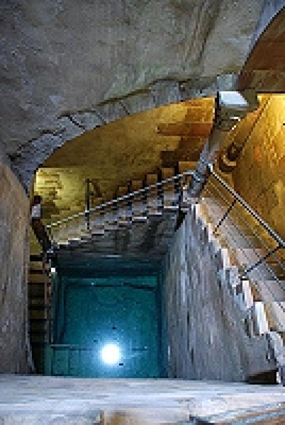 Eine steinerne Treppe mit recht hohen Stufen führt über zwei Absätze hinunter zur Quellebene. Dort in der Tiefe sieht man das klare, bläuliche schimmernde Wasser glitzern.