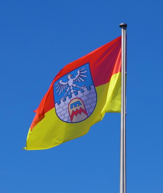 Stadtflagge Dillingen/Saar, Stadtfarben rot-gold, Wappen: Auf blauem Grund eine silberne, gezinnte und gefugte Mauer, darüber ein silberner, goldgekrönter und goldbewehrter Adler mit ausgebreiteten Flügeln und roter Zunge aus dem Wappen Lothringens. In der Mauer ein goldenes Tor mit rotem Rand. Darauf einen roten Zickzackbalken, der von einem dreilätzigen, blauen Turnierkragen überragt wird. Das Wappen lehnt sich in seiner Gestaltung an das Wappen der Edelherren von Siersberg, Herren zu Dillingen (roter Zickzackbalken und blauer Turnierkragen auf Goldgrund) und an das Amtswappen der ehemaligen Prévôté (Vogtei) Siersberg (silberner Turm mit Adler auf blauem Grund) an. Das Wappen der Edelherren wird im Dillinger Wappen zum Tor in einer Stadtmauer umgedeutet.